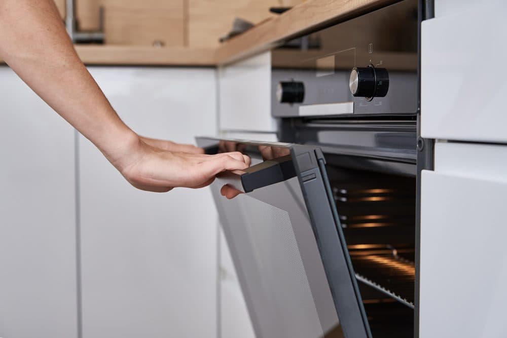 A person is opening their oven with both hands