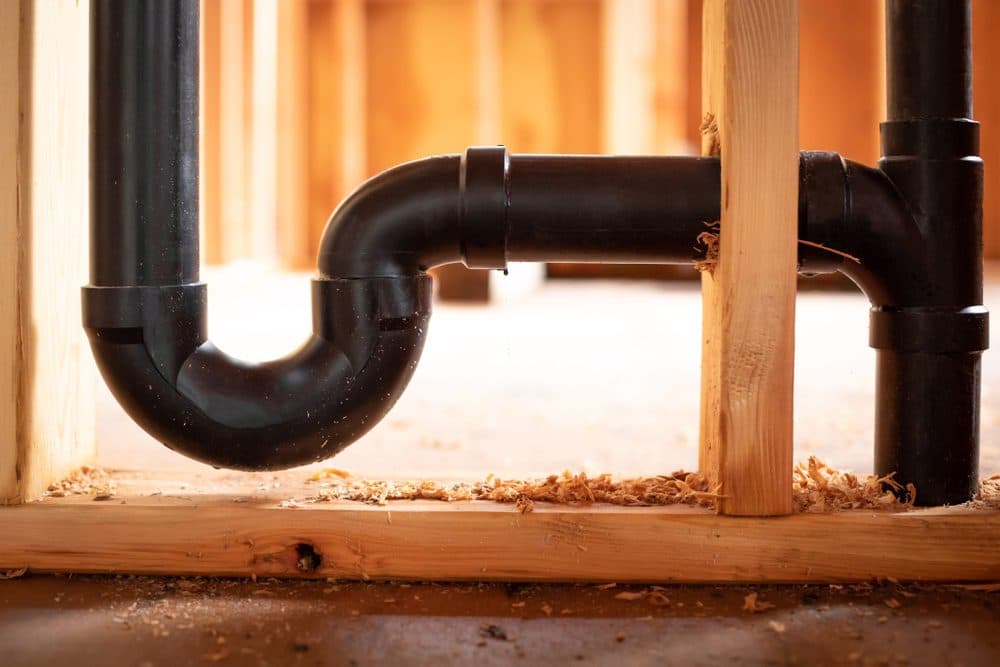 A pipe running through a wooden stud in an unfinished home