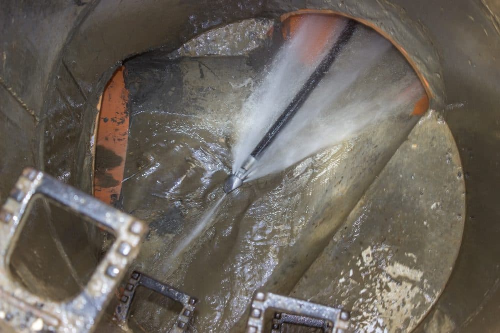 Tools working on a pipe spewing water