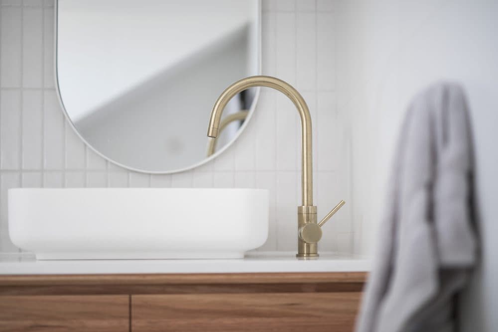 A bronze faucet sitting above a rectangular sink in a bath room