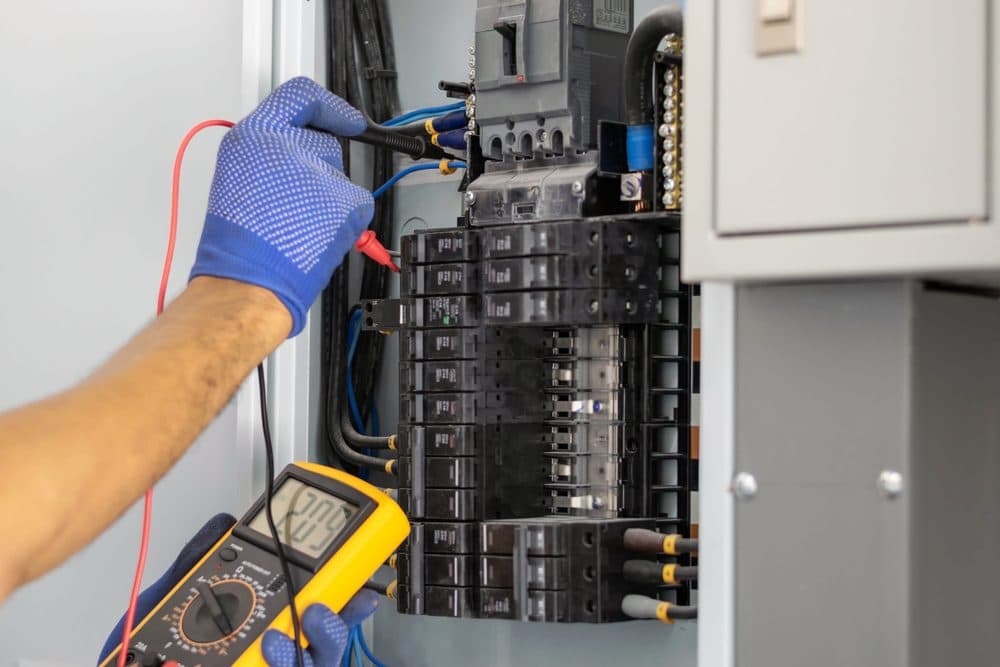A technician using tools to check for issues inside of a panel