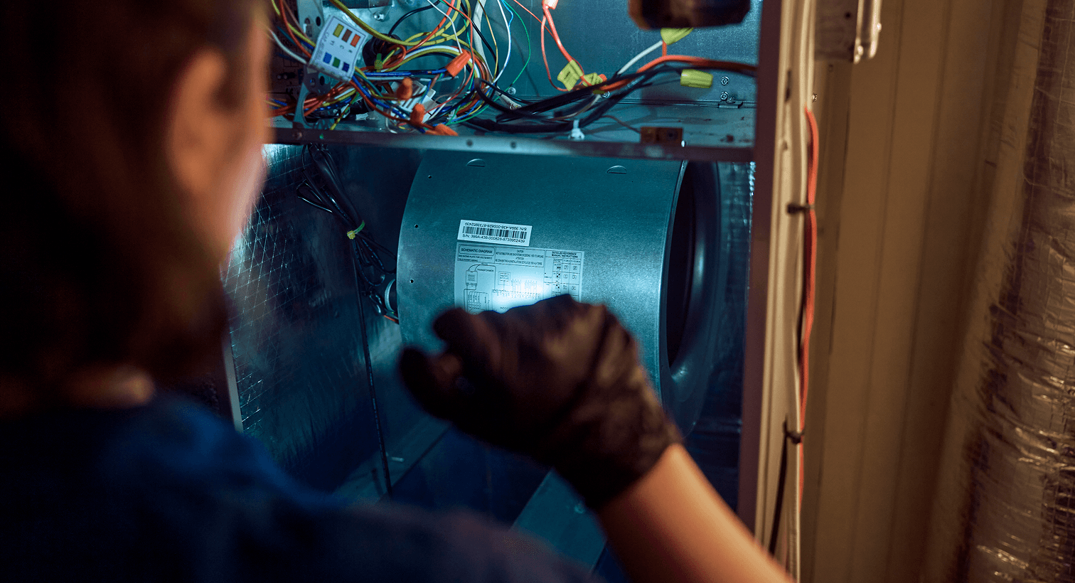 Technician using a flashlight to look at a unit