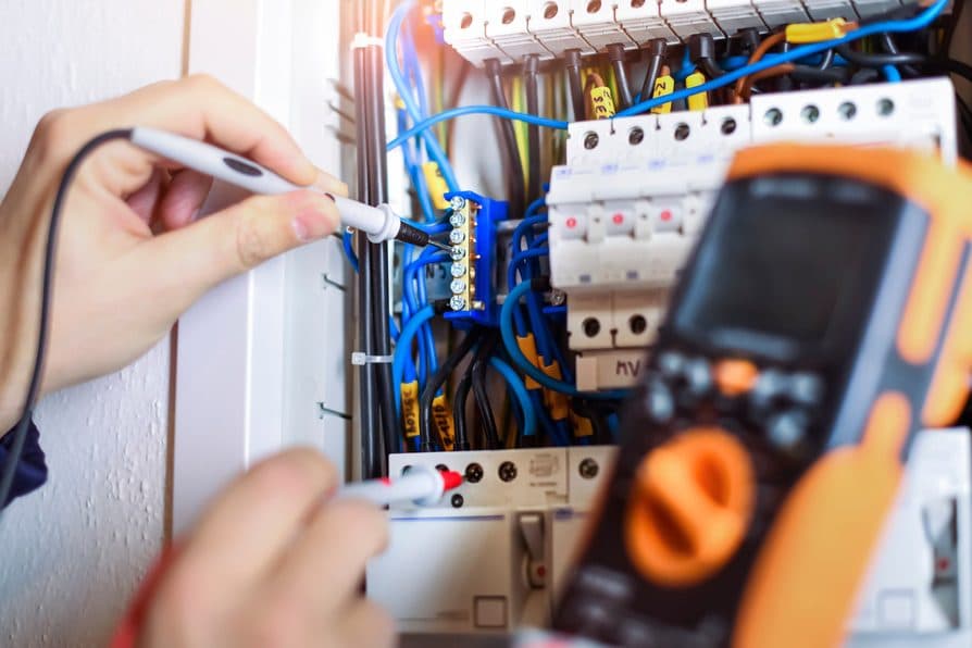 A technician checking wiring with tools a customer