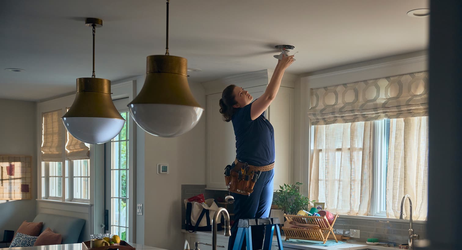 Gold Medal electrician installing a ceiling-mounted light fixture in a residential kitchen