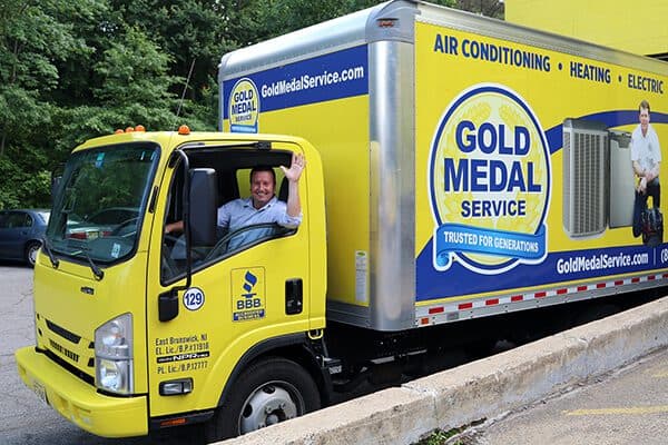 A Gold Medal technician waving to the camera while driving his truck