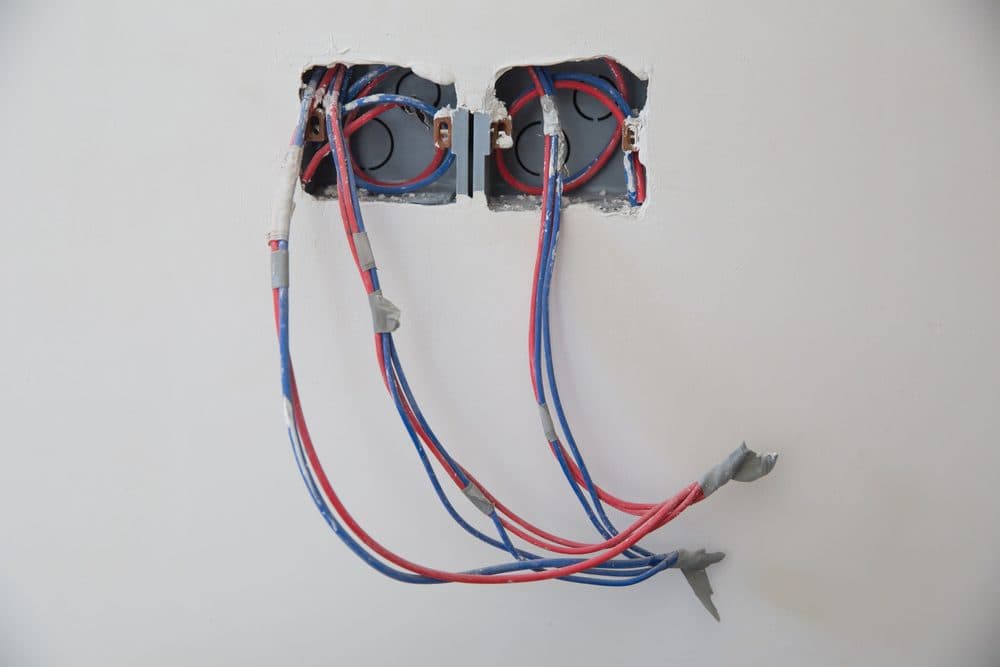 Two sets of electrical wiring coming out of sheet rock