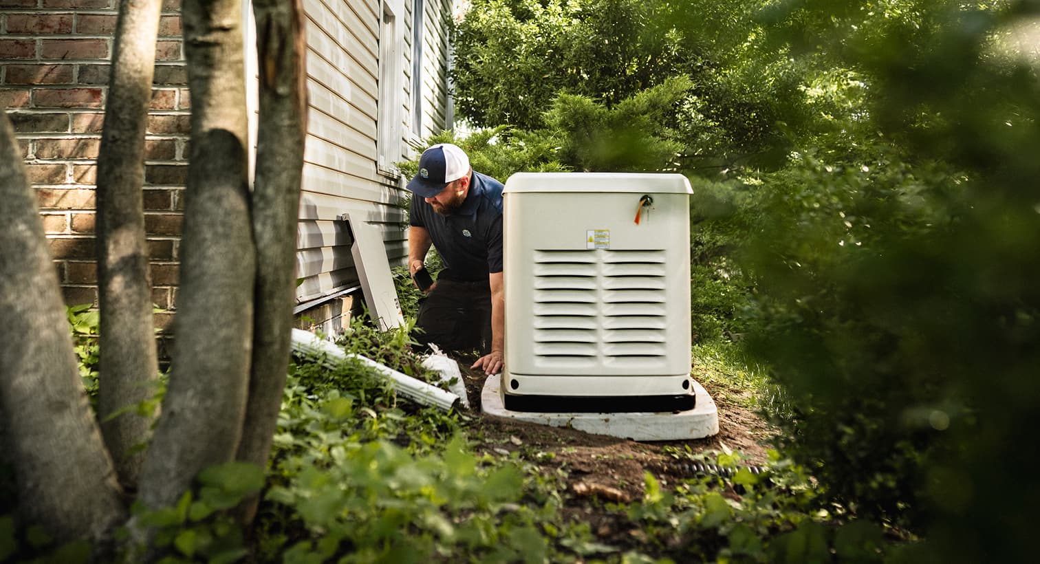 A Gold Medal professional technician inspects a large, beige whole-home standby generator installed on a concrete pad outside a residential house.