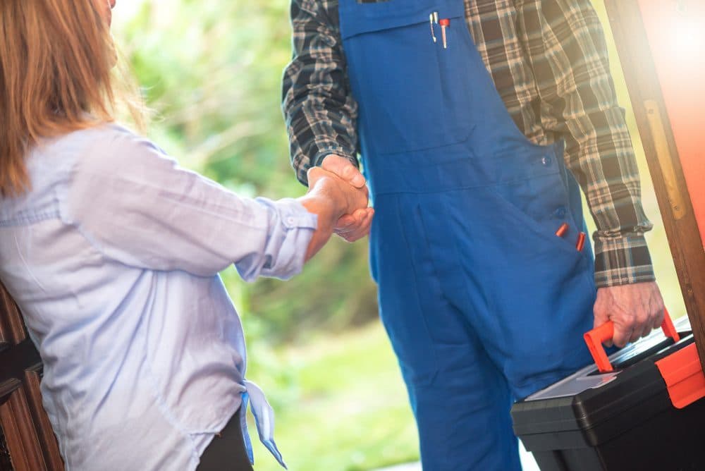 A homeowner and a technician shaking hands at the front door