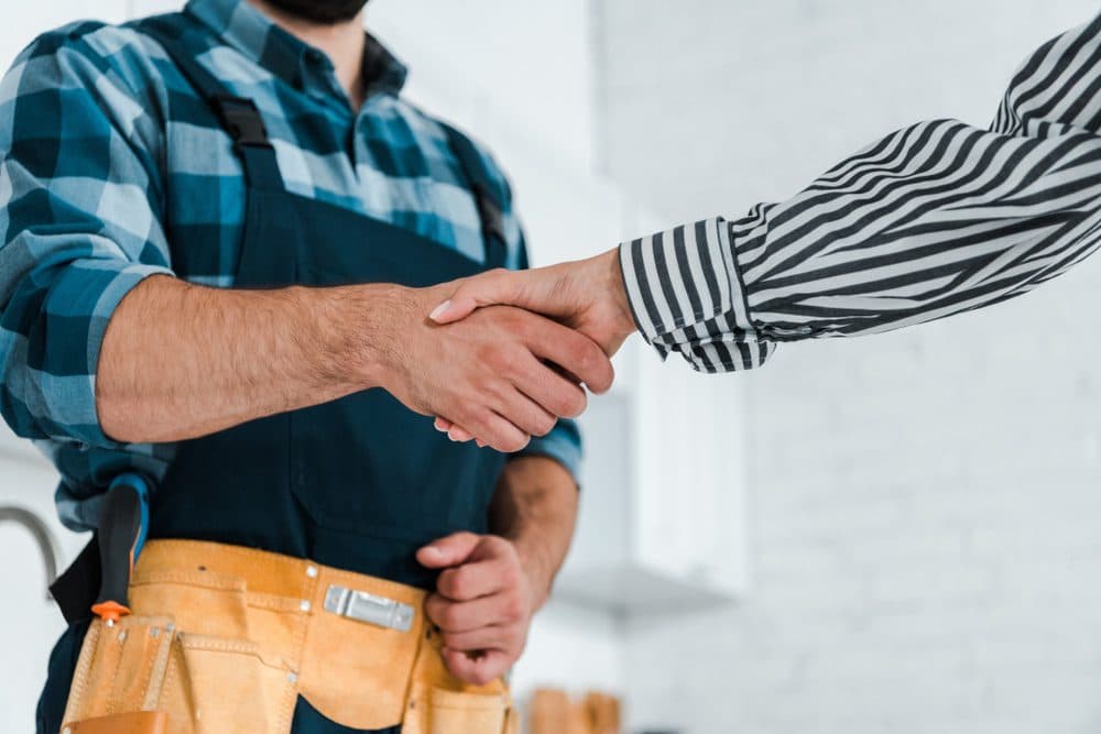 A homeowner and an HVAC technician shaking hands