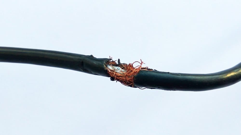 Thick wiring with a large gash exposing the inner bits of it causing it to be susceptible to short circuiting